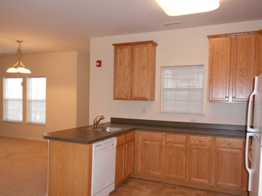 an empty kitchen with wooden cabinets and a white refrigerator