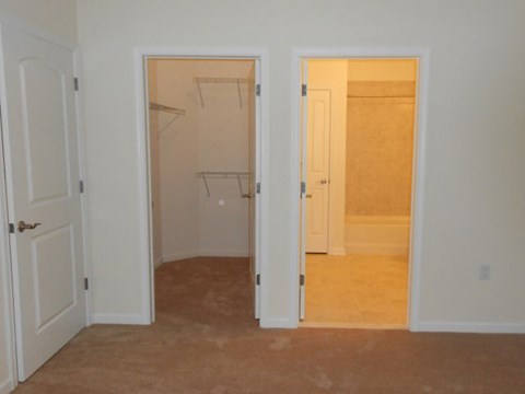 an empty bedroom with two closets and a door to a bathroom