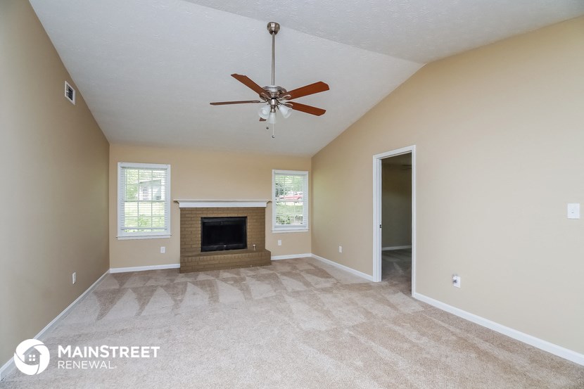 the spacious living room with fireplace and ceiling fan