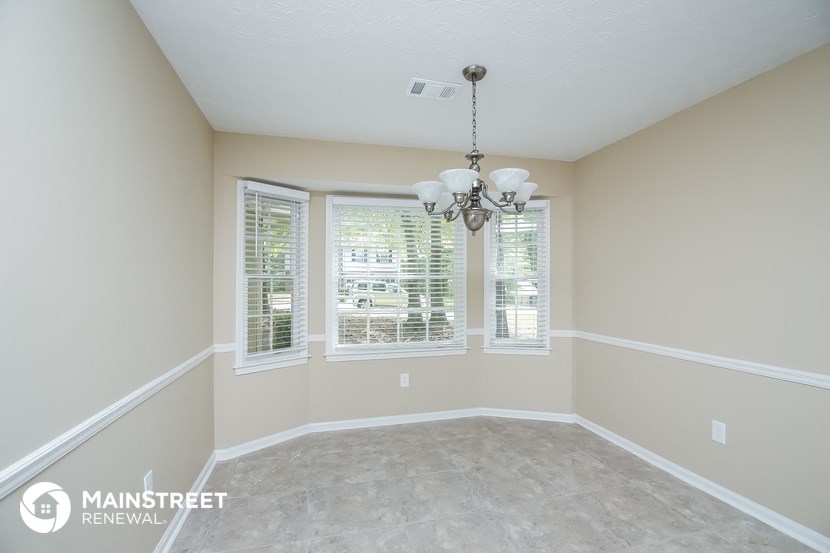 an empty dining room with three windows and a chandelier