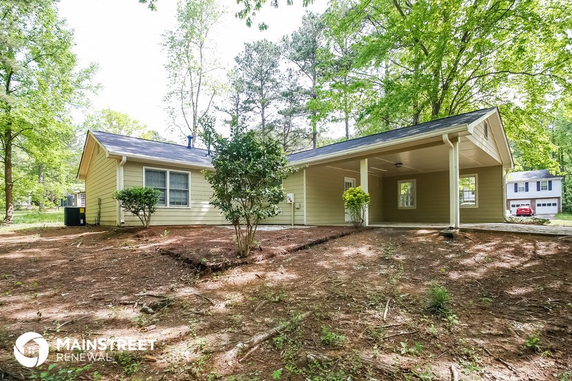 the front of a yellow house with a yard and trees
