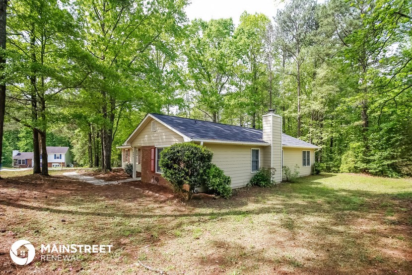 a small yellow house in a wooded area with trees