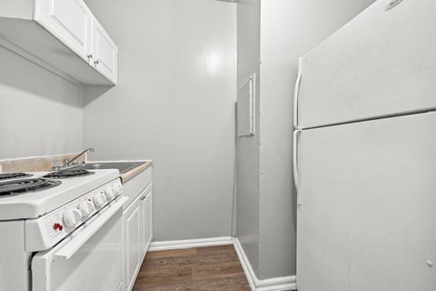 the kitchen of our studio apartment has a white stove and refrigerator