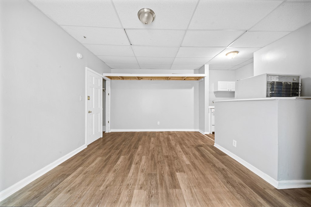 the living room and kitchen of a new home with white walls and wood floors