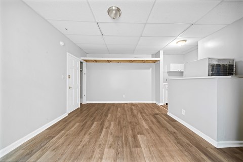 the living room and kitchen of a new home with white walls and wood floors