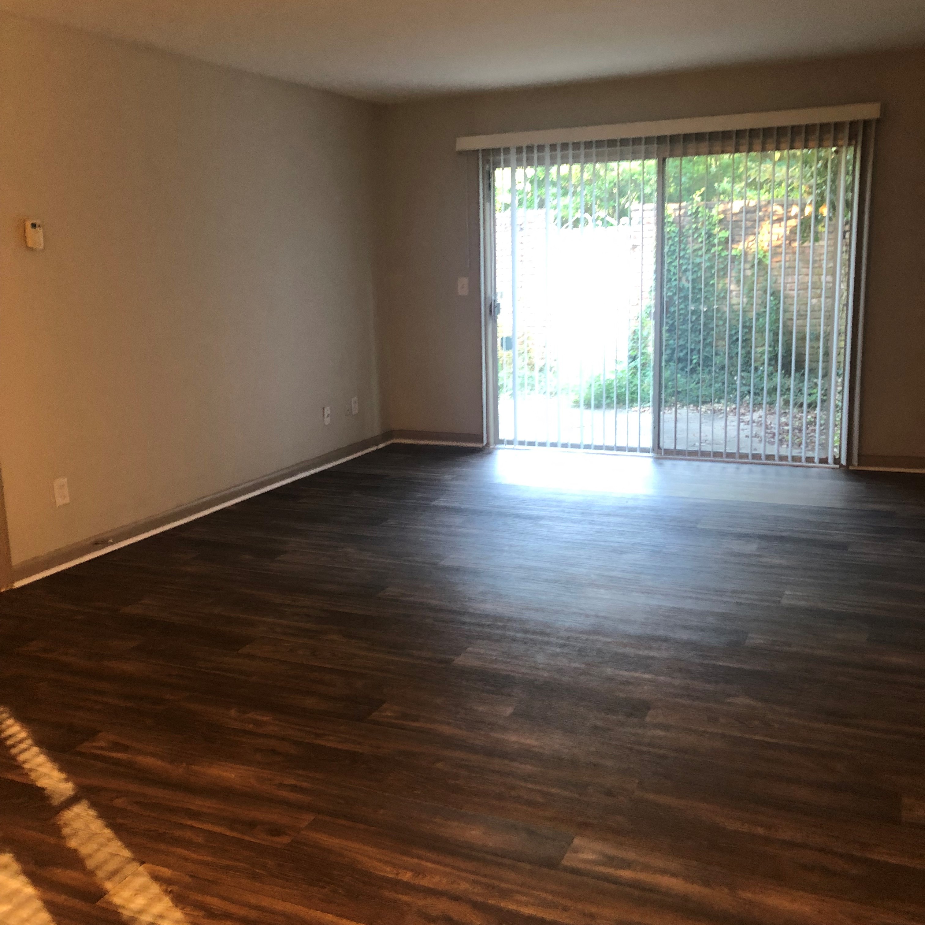 an empty living room with wooden floors and a sliding glass door