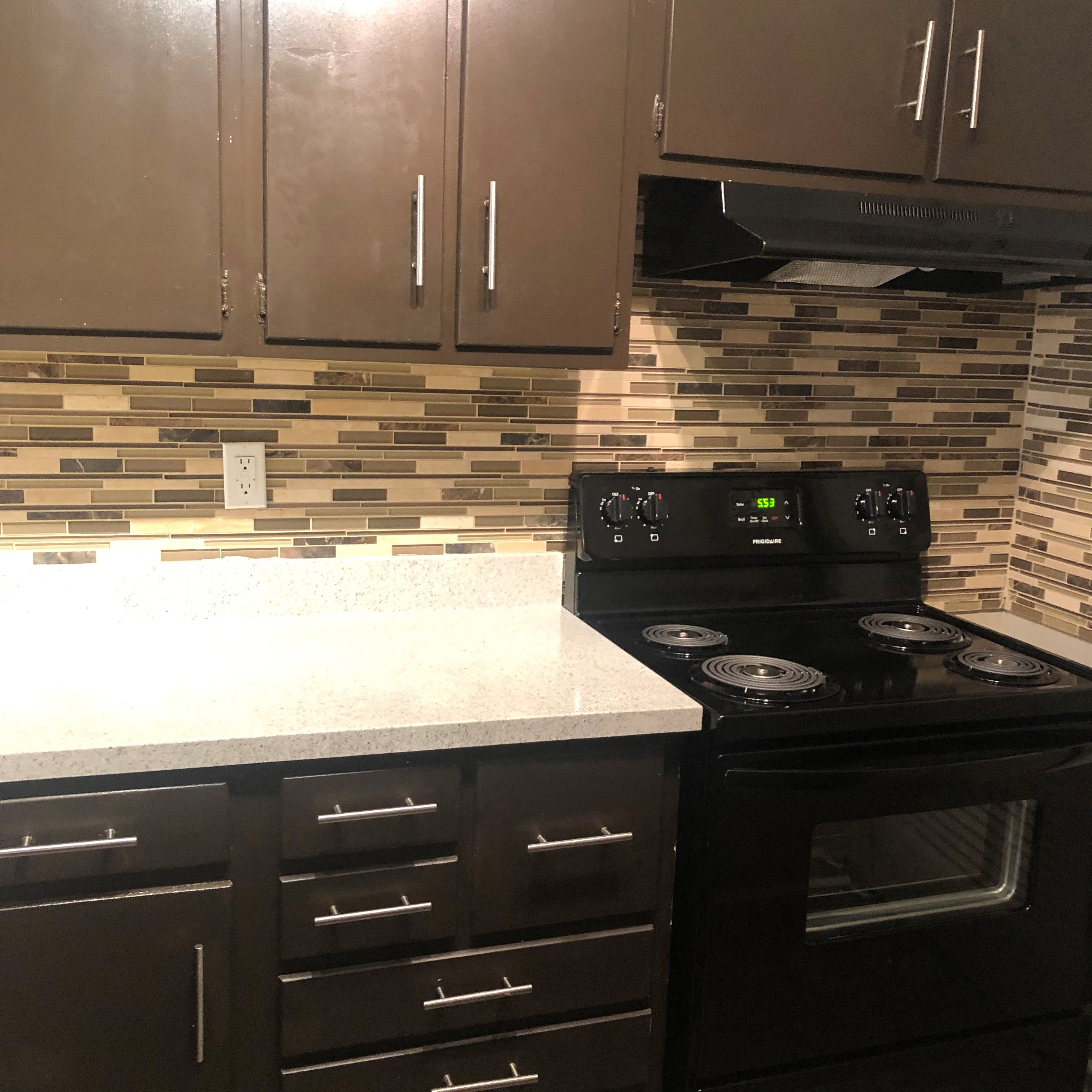 a kitchen with a white counter top and a black stove