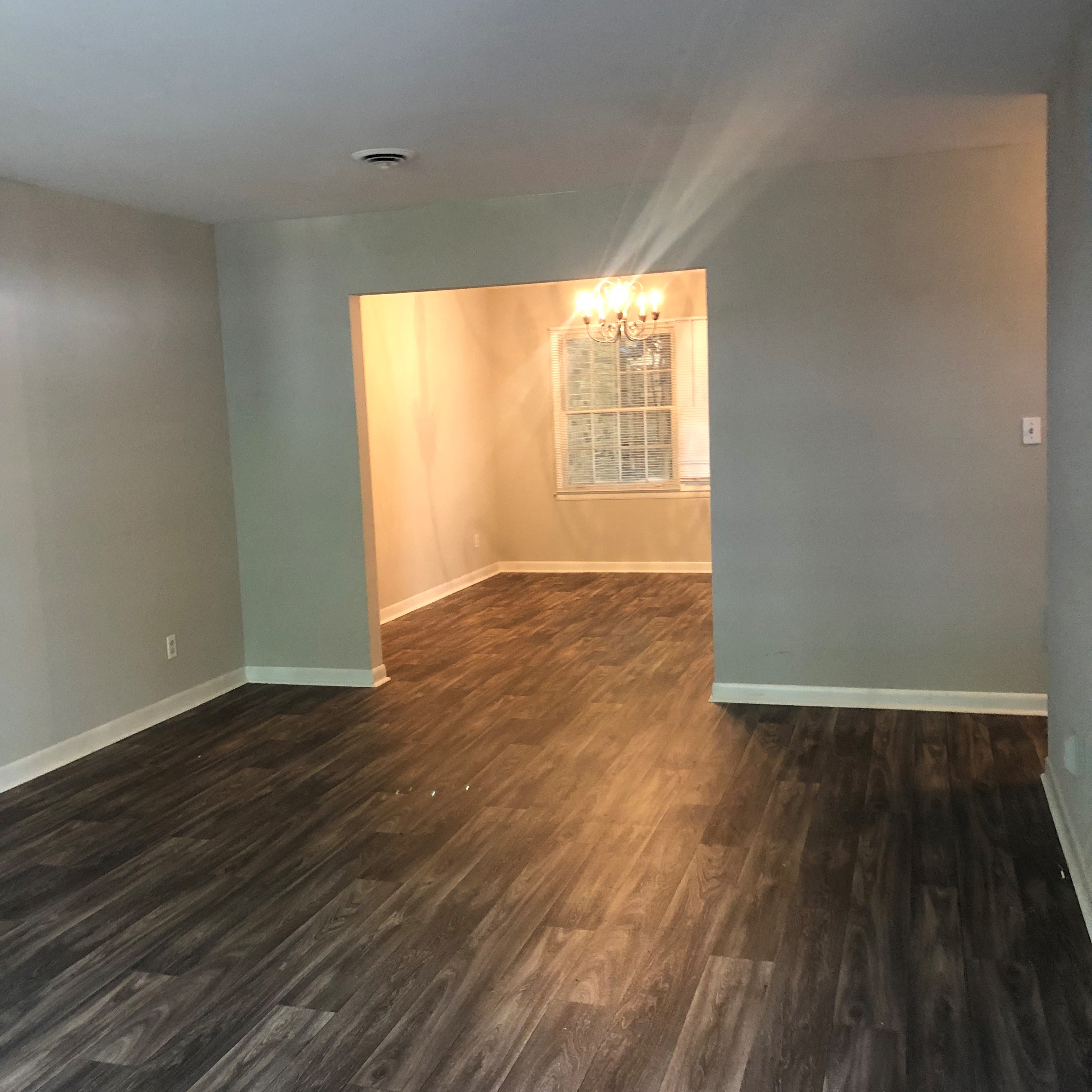 an empty living room with wood floors and a window