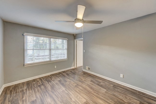 an empty living room with a ceiling fan and a window