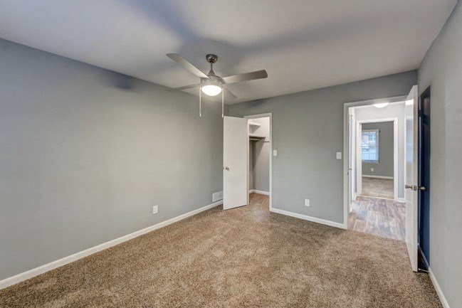an empty living room with blue walls and a ceiling fan