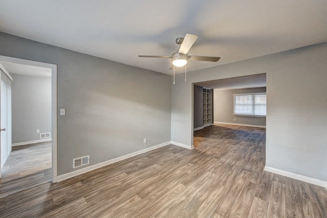 an empty living room with wood floors and a ceiling fan