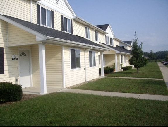 a row of yellow houses with a sidewalk and grass