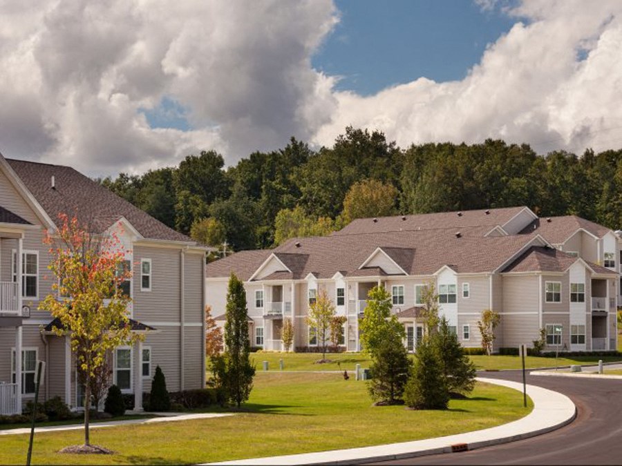a row of town houses on a street with a grass field and trees