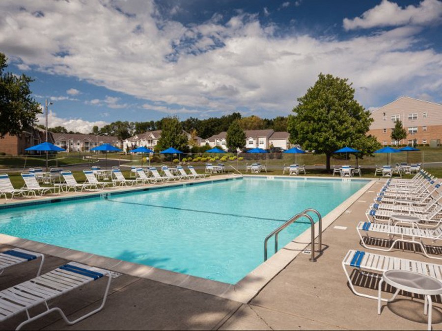 a swimming pool with white chairs and blue umbrellas