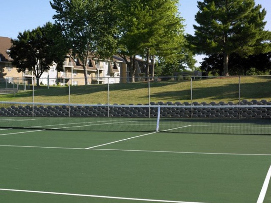 a tennis court with trees and buildings in the background