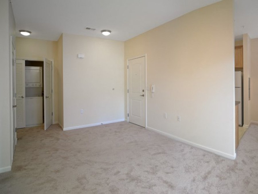 an empty living room with a refrigerator and a door