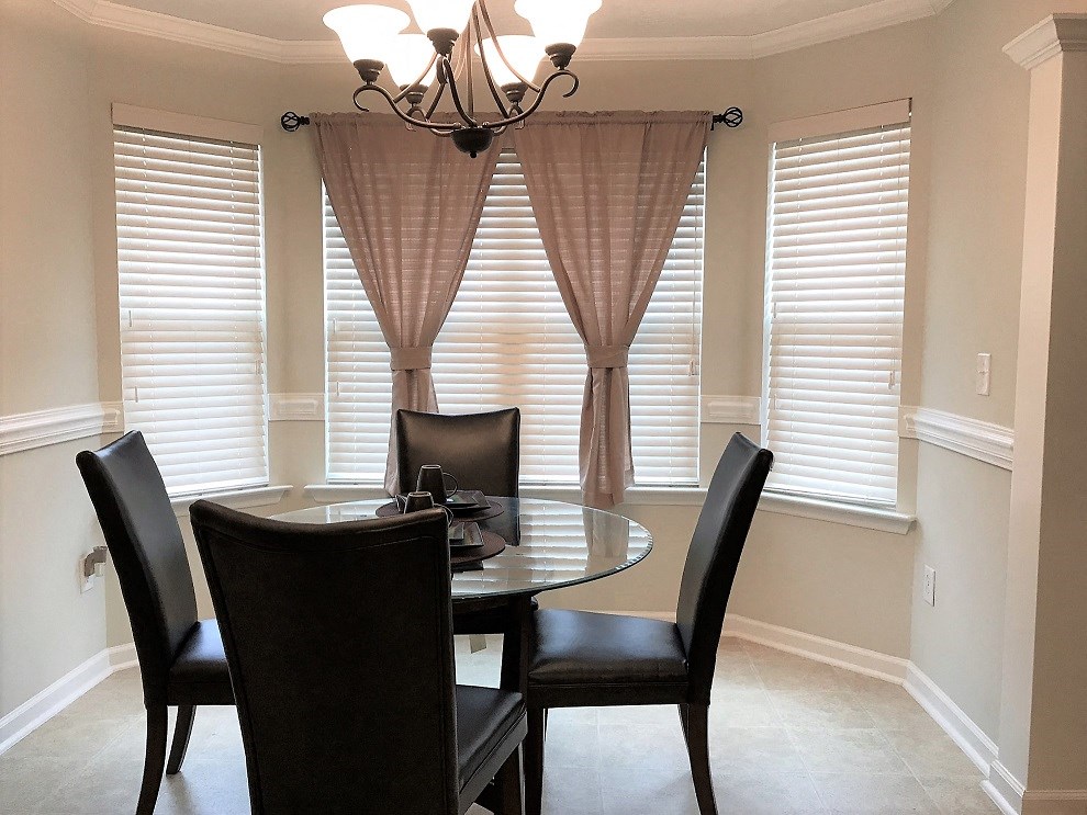 a dining room with a table and chairs and windows with blinds