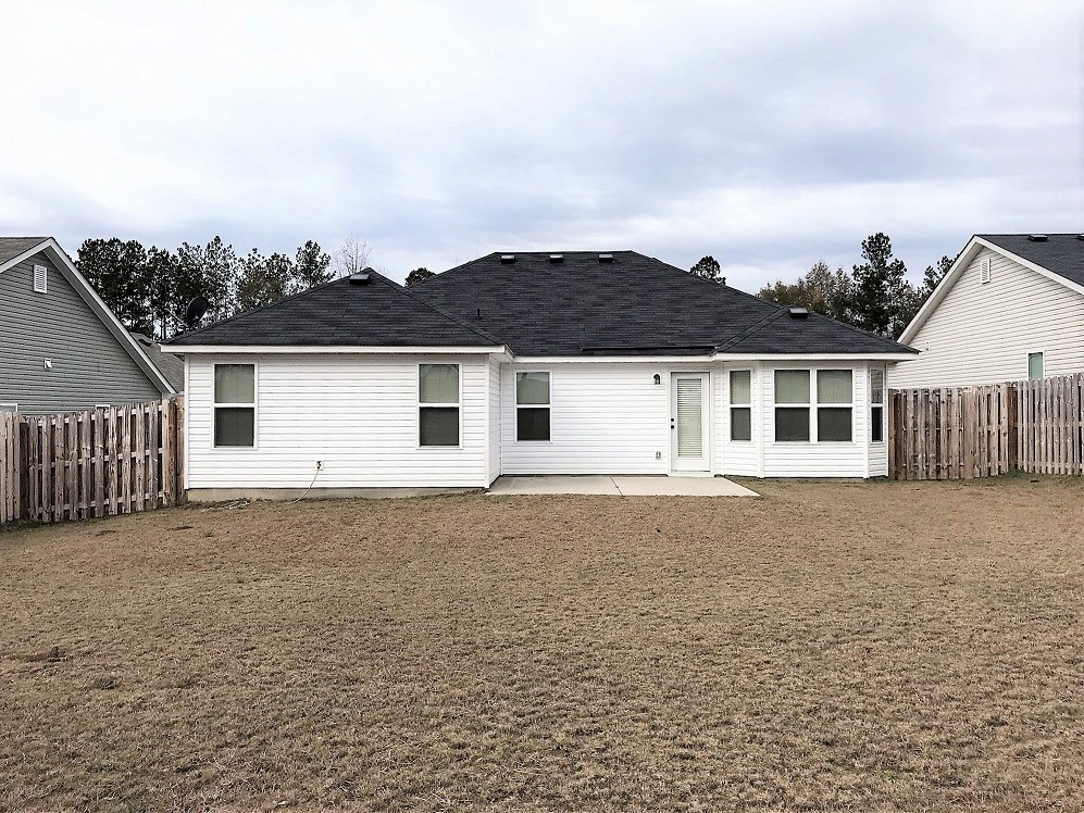 a white house with a black roof and a dirt yard