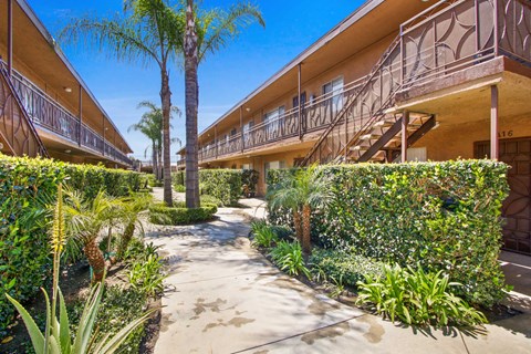 the walkway through the courtyard of a building with palm trees