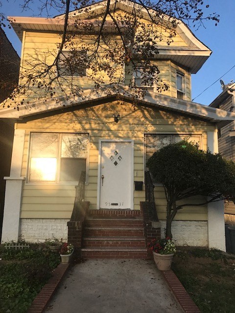 a small yellow house with a white door and stairs