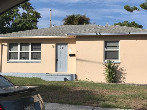 a yellow house with a blue door and a car parked in front