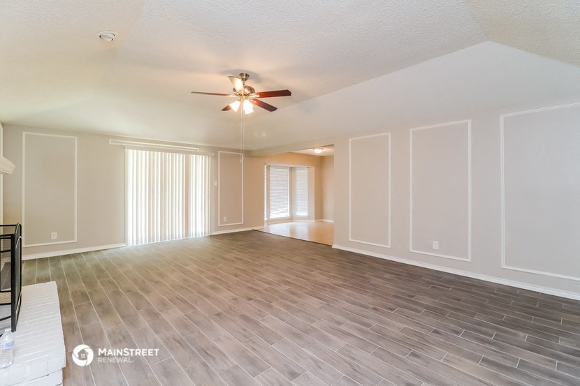 an empty living room with wood flooring and a ceiling fan