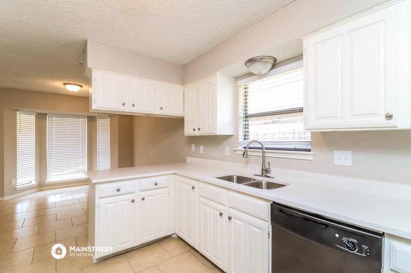 a kitchen with white cabinets and a sink and a window