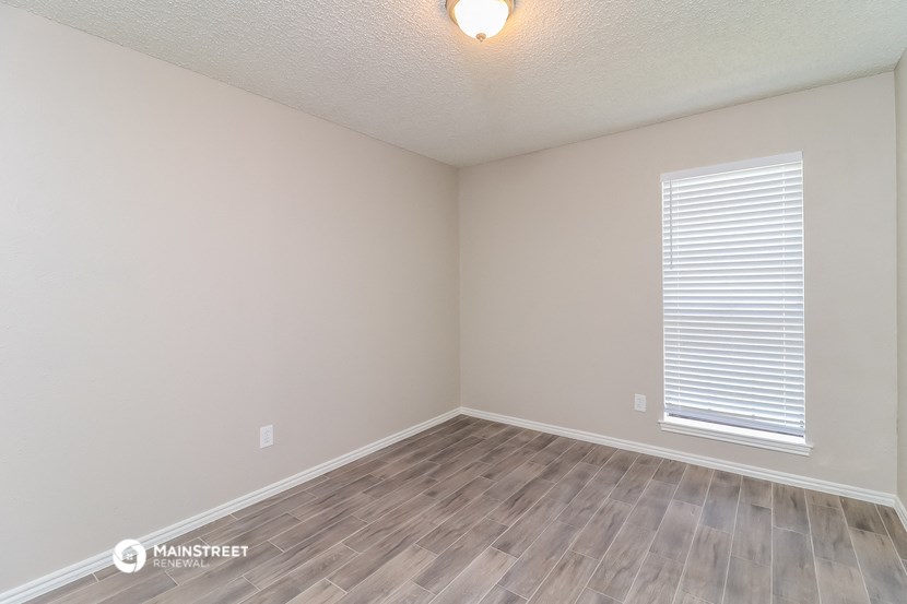 the spacious living room with wood flooring and a window