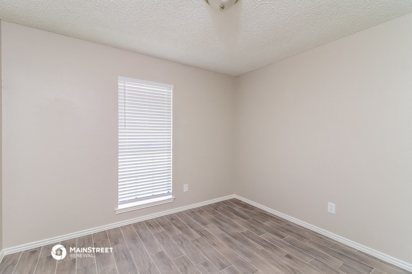 the spacious living room with wood flooring and a window