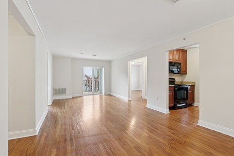 A spacious living room with wooden floors and white walls.