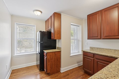 A kitchen with a black refrigerator and wooden cabinets.