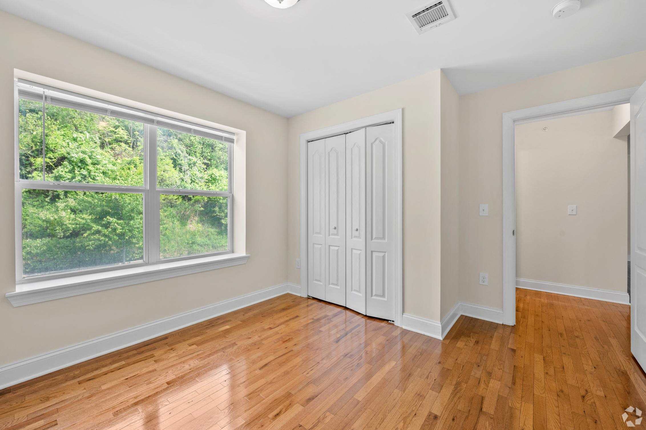 an empty room with wood floors and a large window