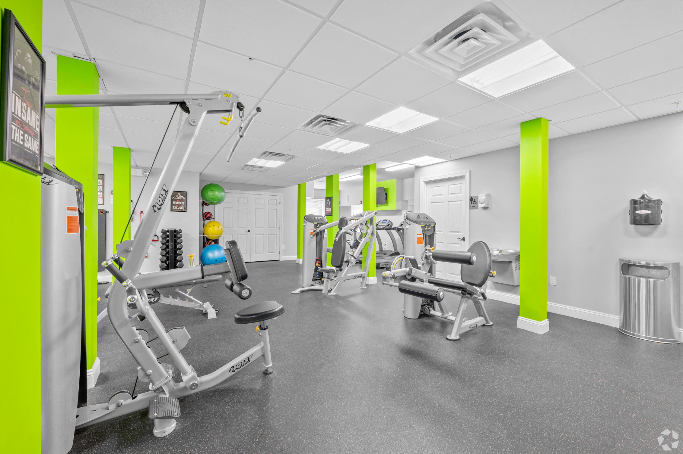 a gym with weights and other equipment in a building with green pillars