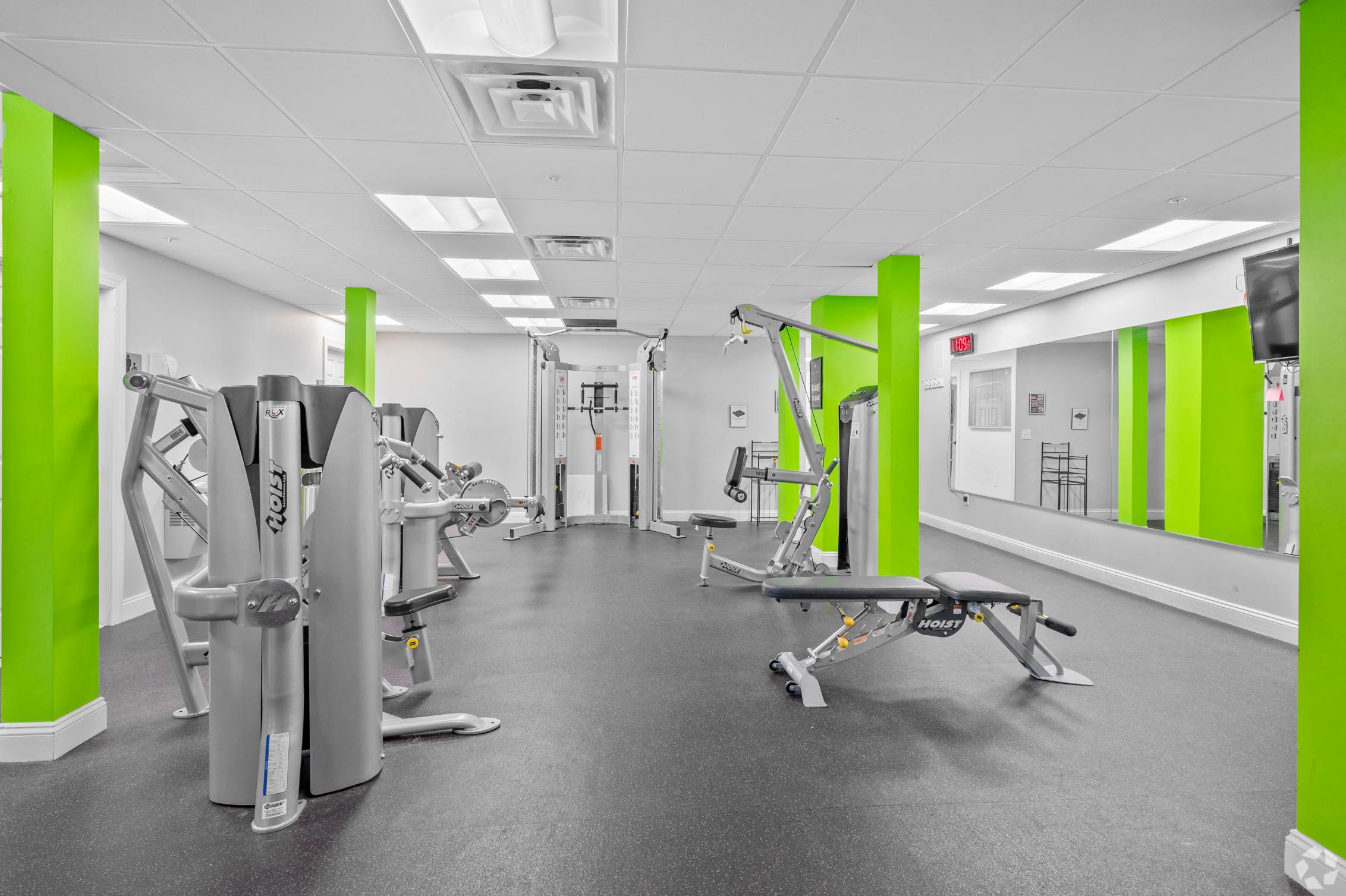 a room filled with exercise equipment and green pillars