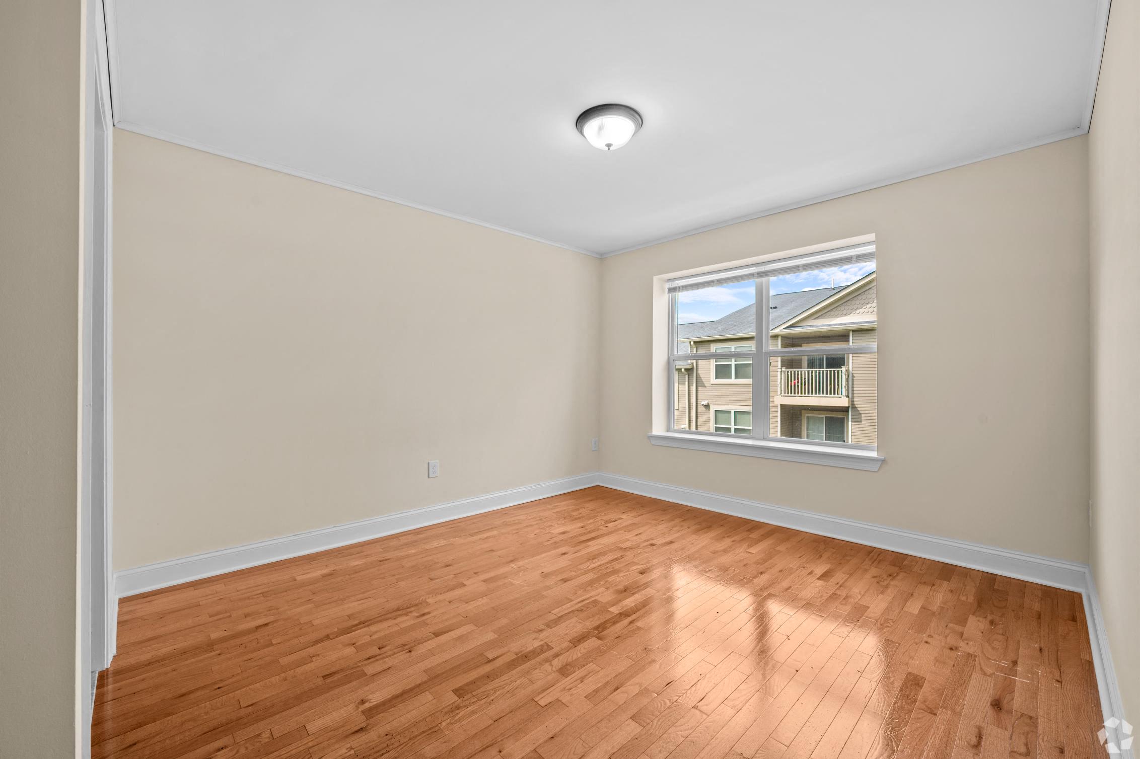 an empty living room with wood floors and a window