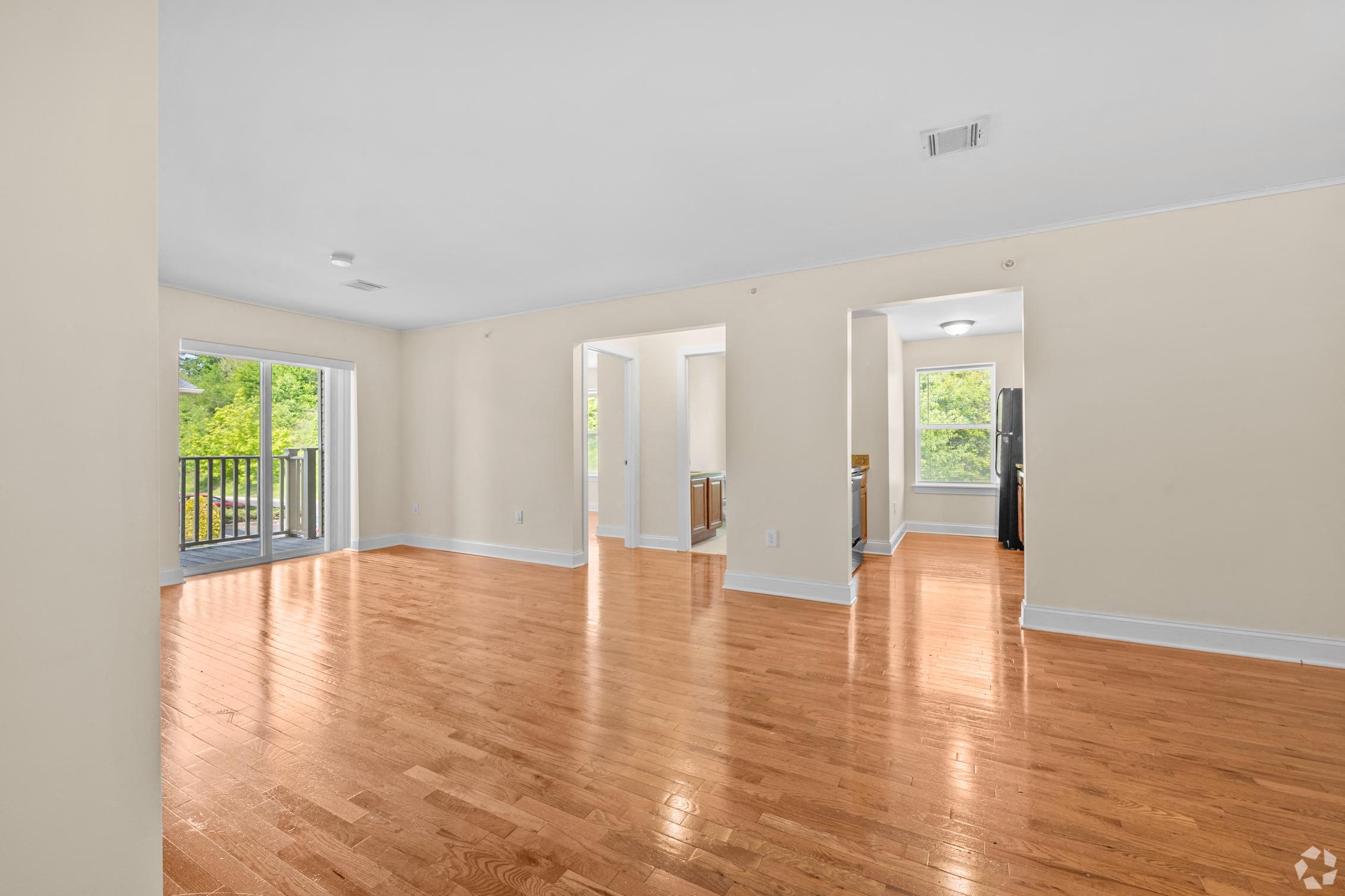 an empty living room with a hard wood floor and a balcony