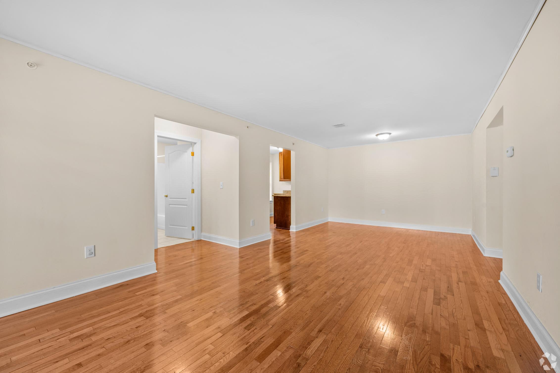 a spacious living room with wood floors and white walls