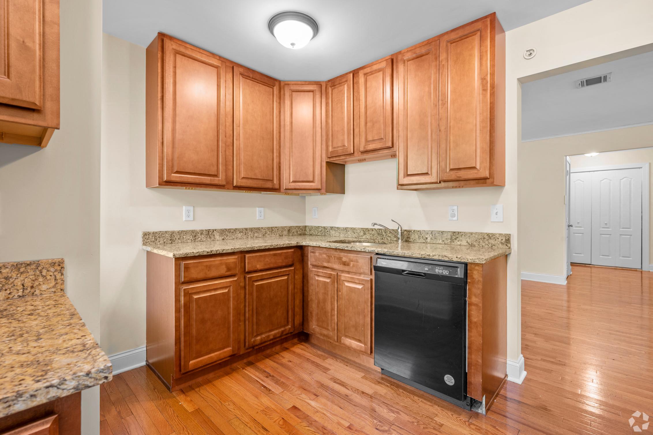 a kitchen with wooden cabinets and a black dishwasher