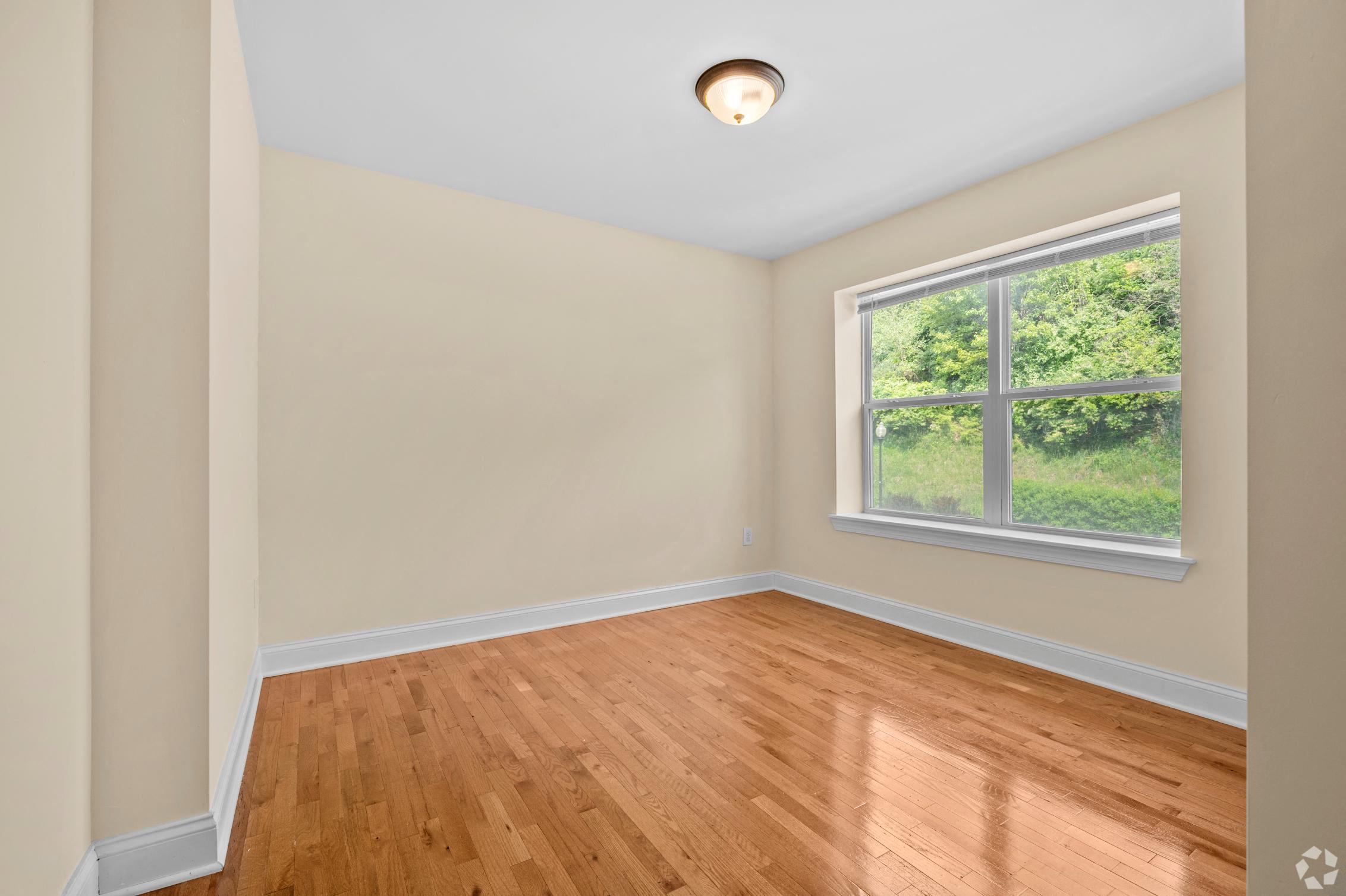 an empty room with wood floors and a window