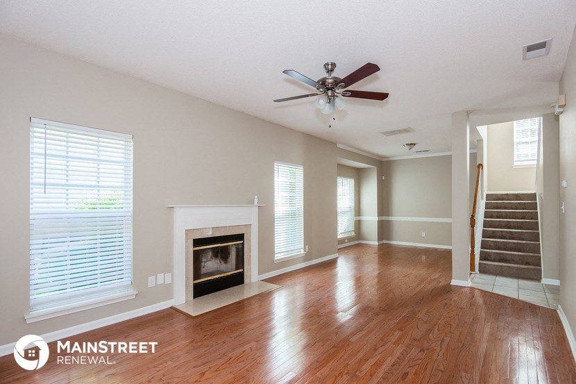 an empty living room with a fireplace and a ceiling fan