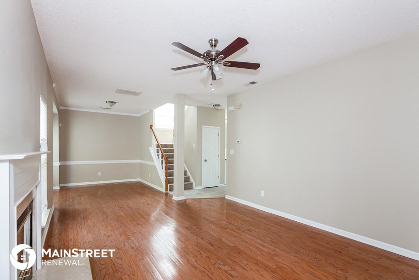 a living room with wood floors and a ceiling fan