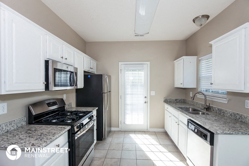 a kitchen with white cabinets and black appliances and granite counter tops