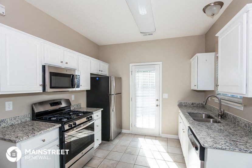 a kitchen with white cabinets and black appliances and granite counter tops