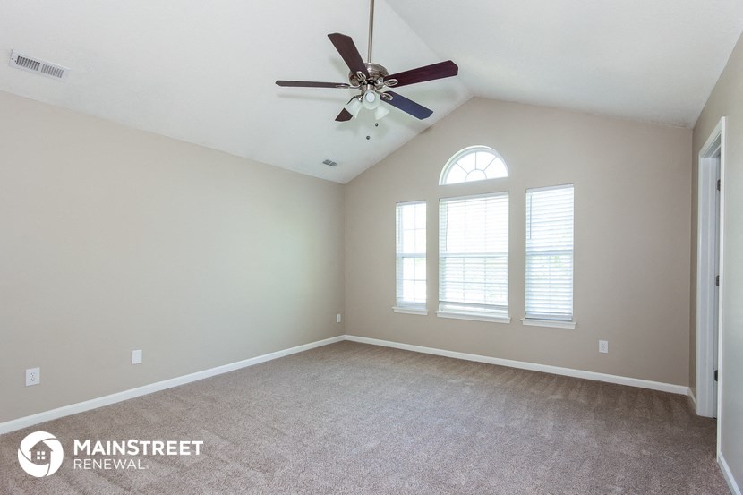 the master bedroom has a large window and carpeted flooring