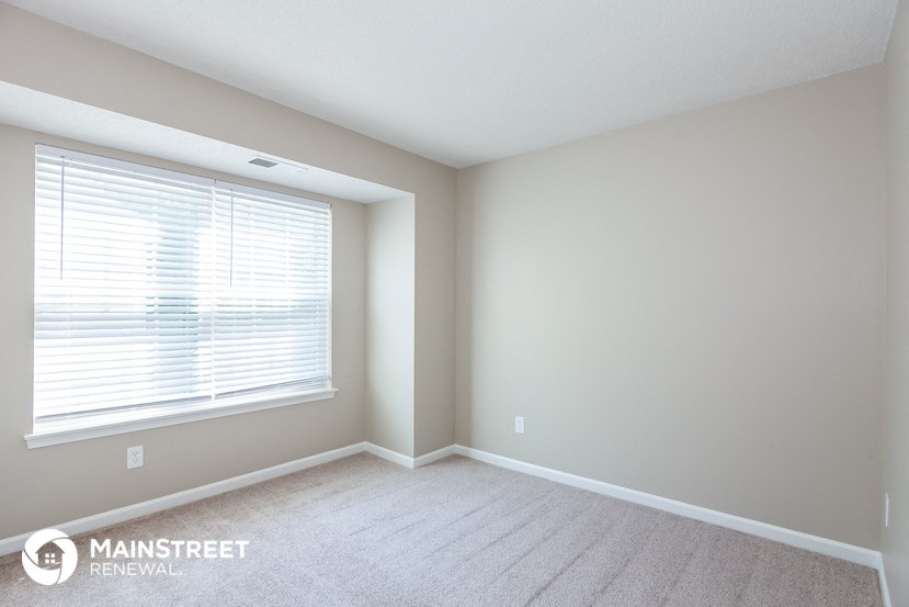 a bedroom with a large window and a carpeted floor