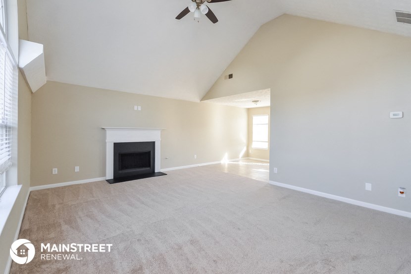 the spacious living room with fireplace and ceiling fan