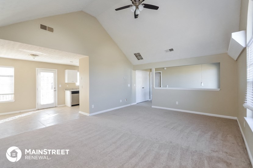 an empty living room with a ceiling fan