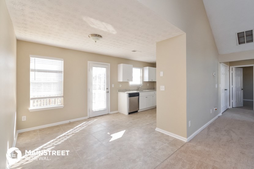 an empty living room with a kitchen in it