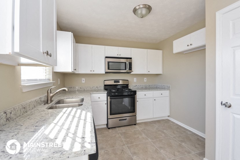 a kitchen with white cabinets and a sink and a stove