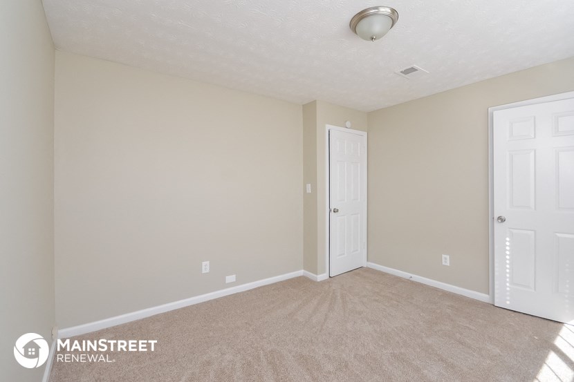 the spacious living room with carpeting and a door to the bedroom
